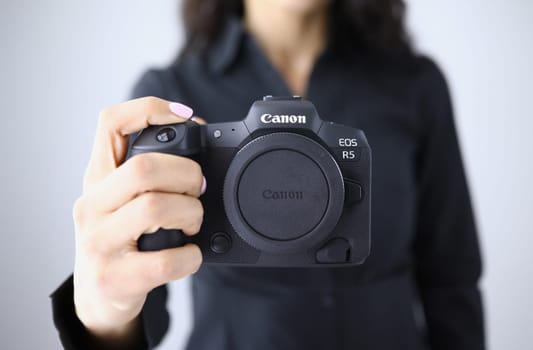 Tbilisi, Georgia - July 26, 2022: Person holding modern Canon EOS R5 camera closeup in hand. Canon mirrorless cameras