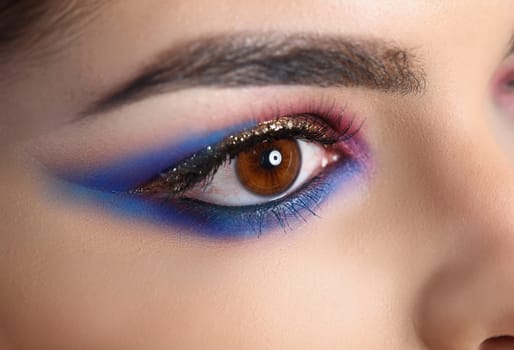 Closeup of brown female eye with beautiful brown red and orange tints smoky eye makeup. Bright evening makeup