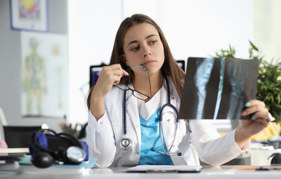 Worried female doctor examining an x-ray of patient. Algorithm for analyzing image quality of radiograph