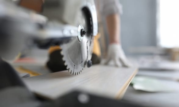 Master cutting piece of laminated wood shelves with manual electric saw in apartment. Laminate cutting machine concept