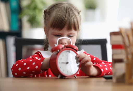 Cute little girl with red alarm clock. Children time for play concept