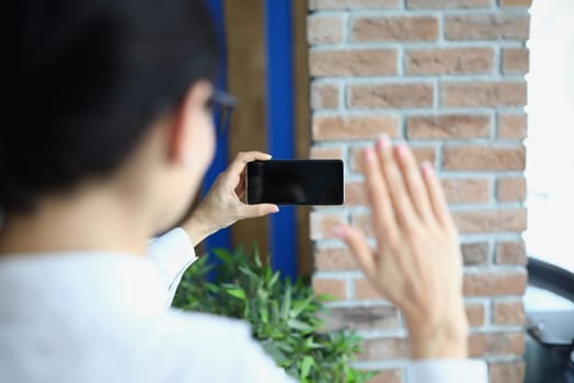 Person video conferencing or phone communication using smart digital mobile phone blank screen. Raise your hand to say hello to teammates online