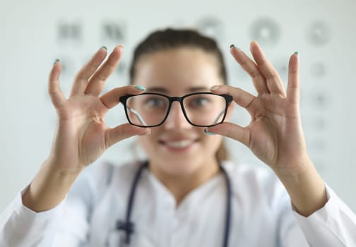 Female ophthalmologist doctor holding glasses in ophthalmology clinic. Optics for vision farsightedness myopia astigmatism concept