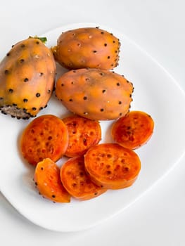 Fresh prickly pears. Whole and sliced on a white plate.