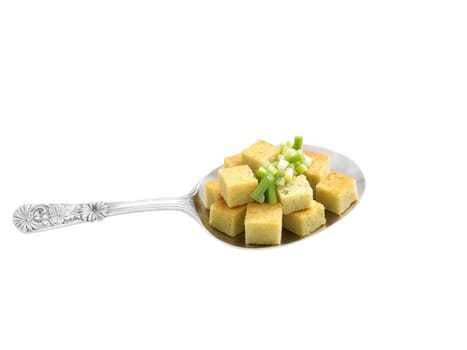 Cornbread stuffing, golden cubes with celery, onion, herbs, on antique silver serving spoon, colorful hero shot on transparent..
