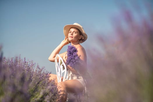 A woman is sitting in a field of lavender flowers and wearing a straw hat. She is smiling and holding a bouquet of flowers. Scene is peaceful and serene, as the woman is surrounded by the beauty of nature.