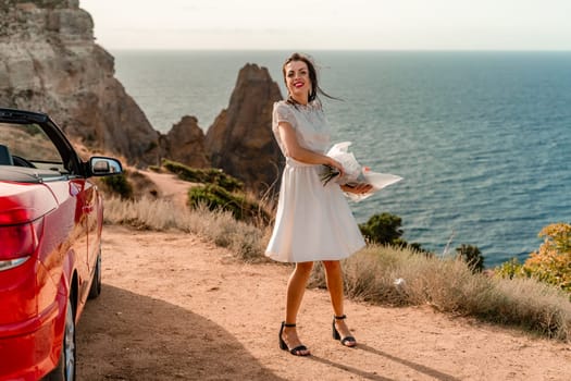 A woman in a white dress is standing next to a red convertible car. She is holding a bouquet of flowers and she is in a happy mood. The scene suggests a romantic or special occasion