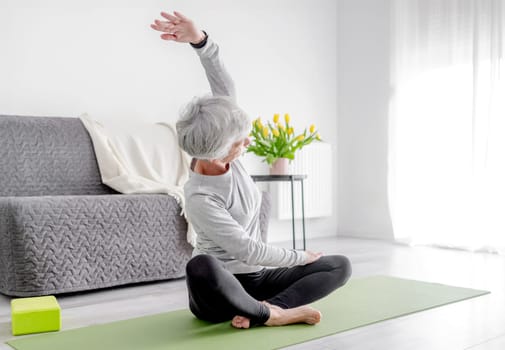 Calm Home Exercises In A Bright Room, A 70-Year-Old Woman Practices Yoga