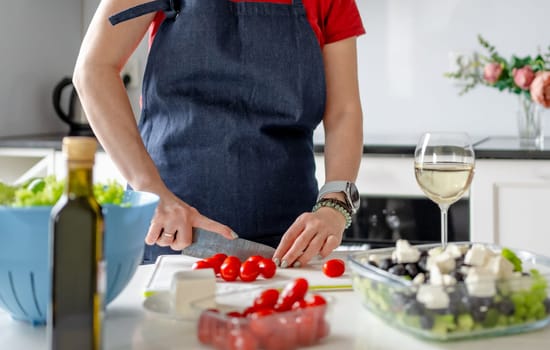 Woman'S Hands Are Slicing Cherry Tomatoes For Greek Salad Preparation At Home