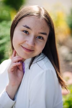 Portrait of a smiling female student enjoying her first day back at school, posing in a lush green garden