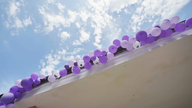 School rooftop adorned with purple and white balloons against a backdrop of a beautiful blue sky with clouds, marking the end of the school year