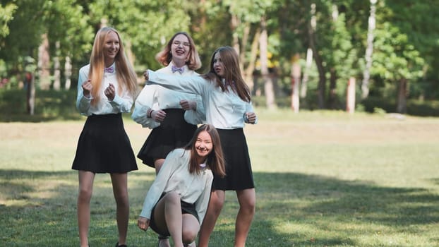 Four cheerful high school students are dancing and having fun together in a park, enjoying their youth and friendship