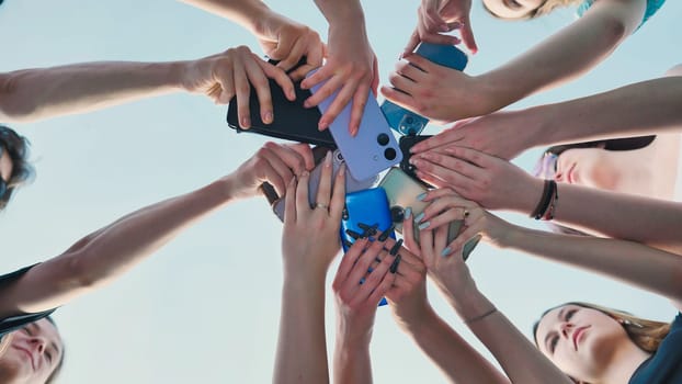 Group of high school students joining their smartphones in a circle, symbolizing connection, sharing, and summer memories