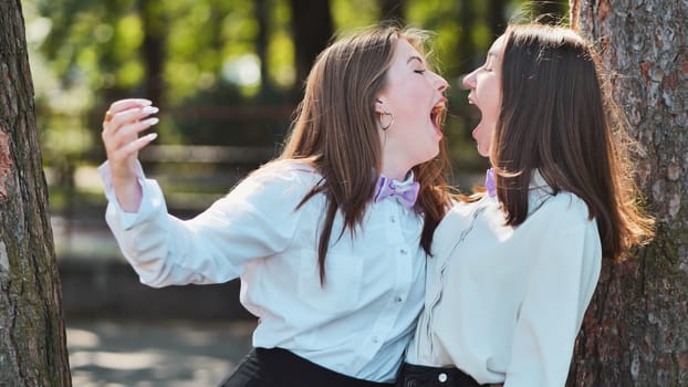 Two students wearing bow ties are screaming to each other in a park during their first day of school