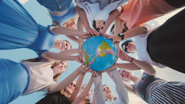 Earth conservation concept. 10 girls and boys surround the rotating earth globe with their palms. A view in motion