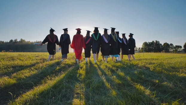 High school graduates walking in a field at sunset, proudly displaying their diplomas and commemorating their success
