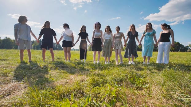 Friends walking through a field on a summer day holding hands