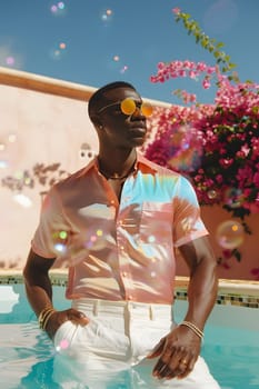 A man in a tie dye shirt and sunglasses is standing in a pool, surrounded by water and plants, under a sunny sky. He looks happy and relaxed while enjoying some leisure time