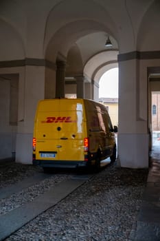 Cremona, Italy - November 20th 2024 Yellow dhl delivery van exiting the arches of palazzo comunale in cremona, lombardy, italy