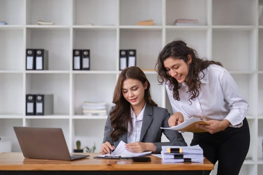 Businesswomen engage in a collaborative discussion with colleagues, fostering teamwork and innovation in a modern office setting.