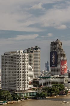 Bangkok, Thailand - 28 Sep, 2024 - Skyscraper view of Shangri-La Hotel and Sathorn Unique Tower with iphone and The icon group advertising signs on Sathorn Unique "Ghost Tower" with Chao Phraya River in the City of Bangkok business district at Afternoon. use it as your wallpaper, poster and Space for text, Selective focus.