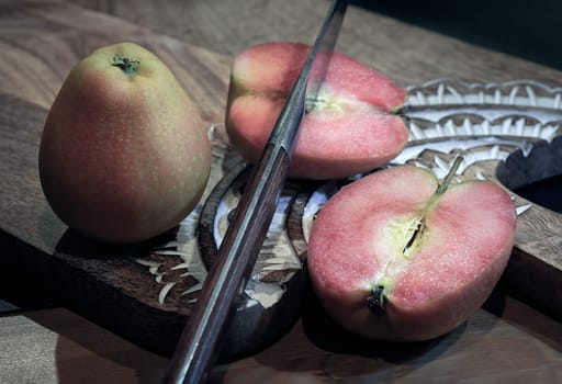 Fresh kissabel apple fruit and Cut the apple in each half with knife on wooden cutting board. Naturally pink flesh kissabel apple with a unique zesty taste, Copy space, Selective Focus.
