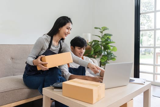 A couple working together in a modern living room, taking online orders and packing products for their e-commerce business.