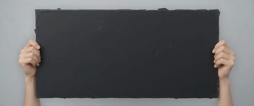 Two hands grip a vast, empty black chalkboard, echoing silence and anticipation. The bare slate looms, a void yearning for expression, in stark contrast to the cool, plain wall. An unwritten symphony of thoughts, a canvas of untold stories, it beckons with an air of mystery and infinite possibilities.