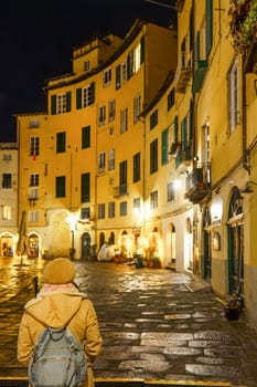 Traveler looking at Lucca's Amphitheatre square at night. Italy