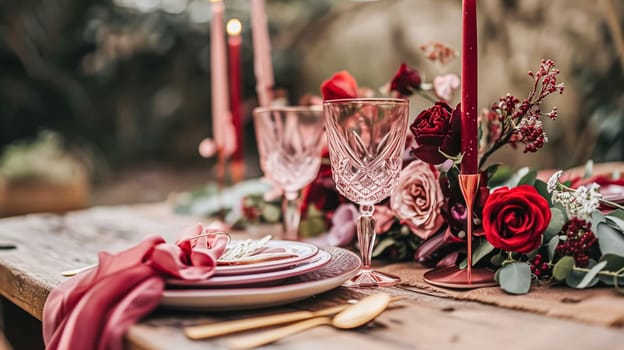 Festive table setting with candles and arrangement of beautiful red flowers. Holiday concept. High quality photo