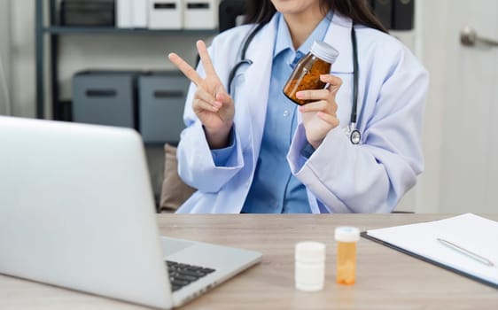 A doctor in a white coat holds a medicine bottle during an online consultation, showcasing modern telemedicine practices.