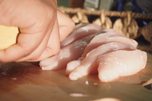 Carefully slicing fresh chicken fillets to prepare for a delicious, appetizing meal treat