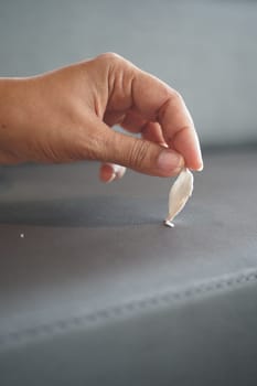 A close-up of removing stuck chewing gum from dark fabric with fingers in focus.