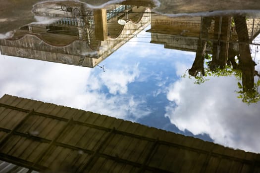 The reflection of the old building is distorted and blurry in the puddle.