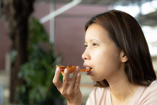 Woman eating a slice of pizza. A woman's hand takes a piece of pizza and puts it into her mouth.