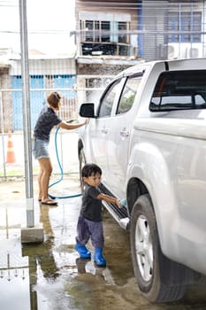 Little child Help his mother washing family car.