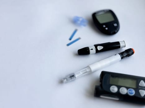 Diabetes management tools. Glucometer, lancets, and insulin pen on white background.