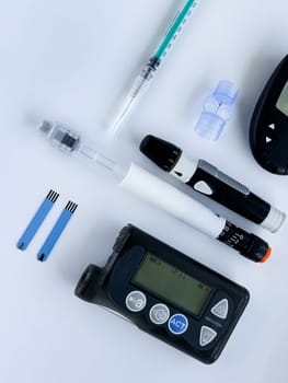 Diabetes management tools. Insulin pump, glucose monitor, and syringes on white background.
