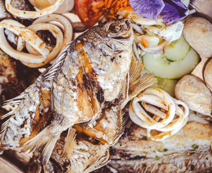 Delicious grilled fish mix plate, a dish with different types of fish, sardines, salmon and seafood, scallops, squid rings from an Atlantic Ocean served in a restaurant in the Canary Islands.