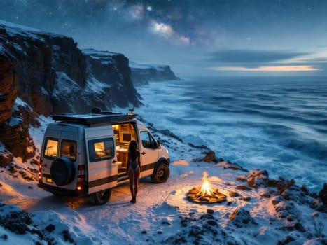 Woman standing next to her camper van, enjoying a bonfire on a snowy cliff overlooking the ocean under the Milky Way. Ai generated