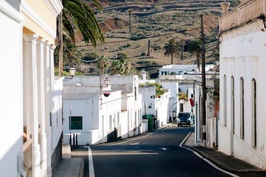 Picturesque streets of a small cozy town with white houses against the backdrop of mountains, view of the road among beautiful buildings on the island of Lanzarote, Canary Islands.