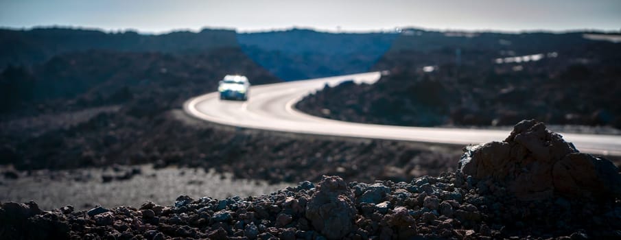 An atmospheric asphalt road among volcanic black basalt lava formations, the path is an empty scenic highway without people running through dramatic volcanic terrain with volcanoes.