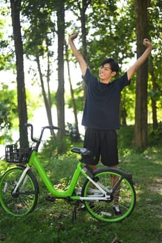 Young man stretching outdoors next to a bicycle in a park. Recreation and outdoor activity concept.