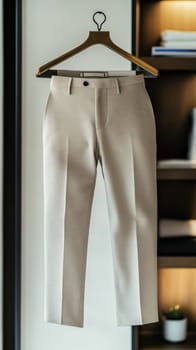 Stylish beige formal suit pants hanging on a golden hanger in a luxurious modern wardrobe, showcasing sophisticated men's fashion