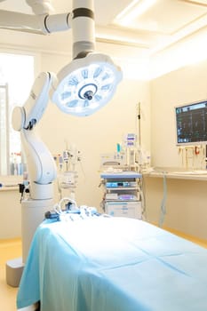 Empty operating room equipped with robotic surgical arm, advanced medical tools, bright surgical lights, and monitoring screen, ready for surgery