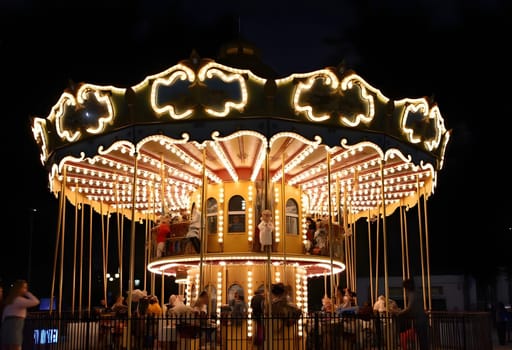 A magical nighttime scene featuring a vintage carousel illuminated by twinkling lights, creating a whimsical and festive atmosphere.
