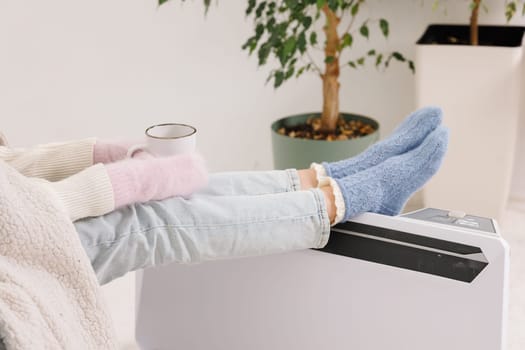 Young girl in warm clothes and with a cup of tea at home. Heating season concept.