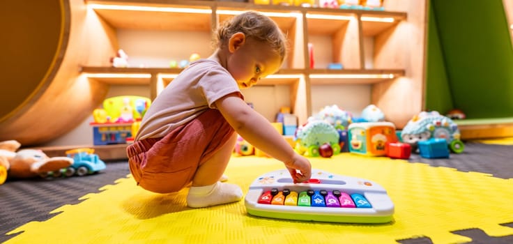 Toddler playing with a colorful toy piano in a bright indoor playroom