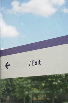 A prominently displayed clear exit sign featuring a directional arrow set against a scenic backdrop