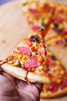holding cheese pizza on blue background .
